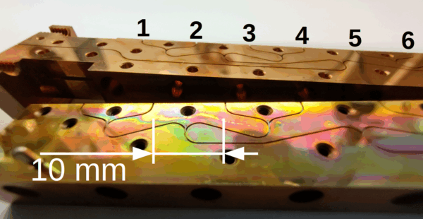 Photograph of the two split-block halves of the 8-way power divider, showing the waveguides with the isolator chips. Output ports are numbered.